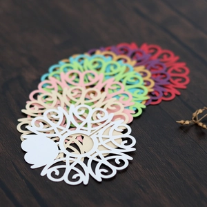 Detailed laser-cut paper wine glass place cards in various colors on wooden surface