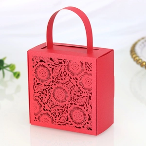 Detail of red laser-cut candy box with intricate floral hollow pattern and curved handle