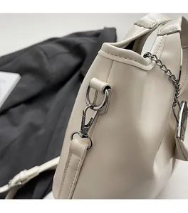Detailed close-up of beige leather bucket bag with silver metal chain and hardware