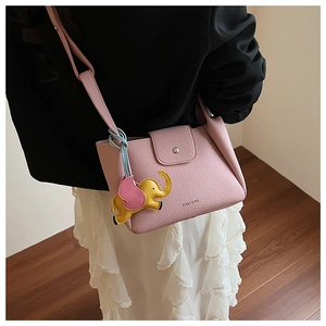 Close-up of pink lychee grain leather bucket bag with cute elephant charm and metal clasp