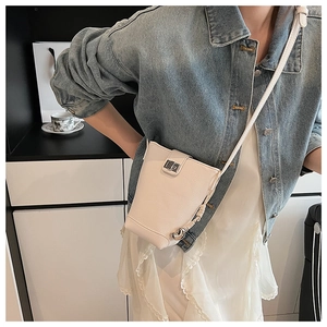 Detail of cream crossbody phone bag with silver heart charm and metal twist lock