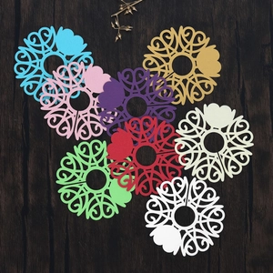 Colorful laser-cut paper coasters featuring intricate heart and scroll patterns on wood