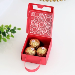 Macro view of red laser-cut floral patterns on wedding candy gift box with handle