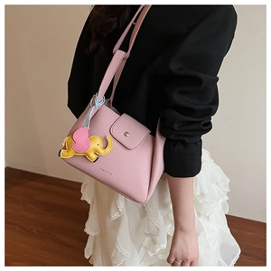Detail view of pink lychee leather tote with a vibrant elephant charm and logo
