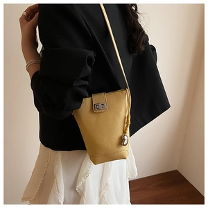 Detail of yellow lychee grain leather bucket bag with silver twist lock on a model