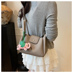Close-up of khaki pebbled leather bucket bag featuring a cute elephant charm
