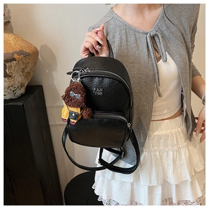 Détail d'un mini sac à dos en cuir PU noir avec un joli pendentif ours en peluche