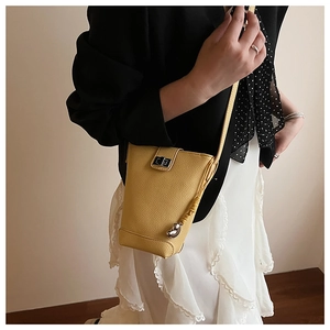 Fashionable bright yellow bucket bag in pebble leather with silver metal charms shown on a model