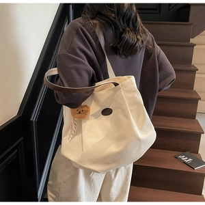 Mannequin portant un grand sac cabas en toile beige avec lanières en cuir et ours