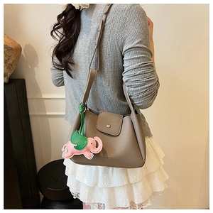 Close-up of taupe litchi grain leather shoulder bag with a cute elephant charm