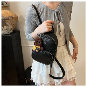 Détail du mini sac à dos noir grainé avec logo PAN TOR et breloque peluche de chien