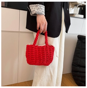 Detail of red woven handbag with white drawstring inner pouch held by a model