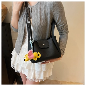 Close-up of black lychee grain leather bucket bag with pink and yellow elephant charm