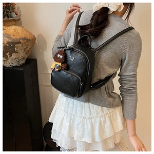 Mini sac à dos en cuir grainé noir avec charme d'ours en peluche porté par un mannequin
