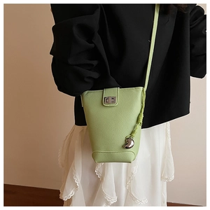 Detail of light green bucket bag with silver twist lock and moon pendant accessory