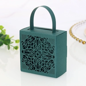 Detail of dark teal paper favor box with intricate laser-cut floral lace patterns