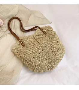 Detail of hand-stitched X pattern on straw tote bag with brown faux leather straps