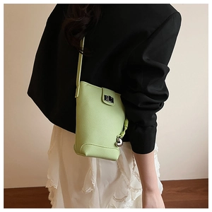 Detail of avocado green bucket bag with lychee texture leather and silver heart charm