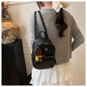 Détail d'un mini sac à dos noir à motif litchi avec un joli pendentif ours en peluche
