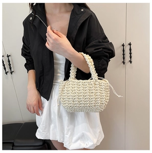 Dettaglio della borsa in maglia crema con manici spessi e coulisse su una modella