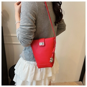 Detail of red bucket bag featuring a silver twist lock and heart-shaped charm