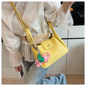 Detail of yellow pebbled leather bucket bag with cute pink elephant charm and strap