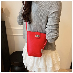 Detail of red pebbled leather bucket bag with silver heart charm on model's outfit