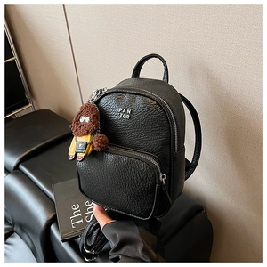 Détail du mini sac à dos noir en cuir grainé avec breloque ours et logo en métal argenté