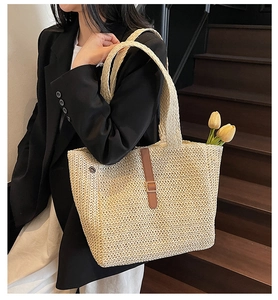 Détail d'un grand sac cabas de plage en paille avec boucle en cuir brun et texture tressée