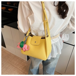 Detail of yellow bucket bag with lychee texture, handles and a cute elephant charm