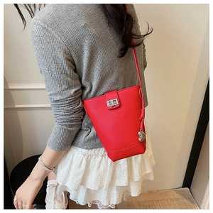 Detail of red bucket bag showing litchi grain leather and silver heart charm pendant