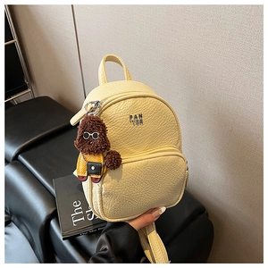Détail du sac à dos en cuir beige avec logo PAN TOR et breloque chien en peluche mignonne