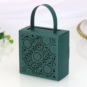 Detail of dark green laser-cut floral paper gift box with handle for wedding favors