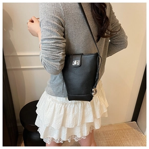 Detail of black pebbled leather bucket bag featuring a silver heart charm and twist-lock
