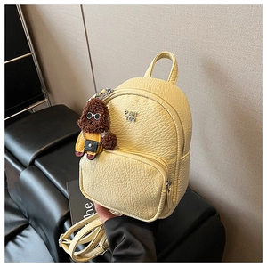 Détail d'un mini sac à dos en similicuir plissé jaune clair avec pendentif ours en peluche
