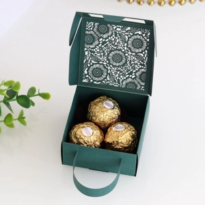 Detail of dark green laser-cut wedding candy box with elegant hollow flower patterns