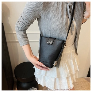 Detail shot of black pebbled leather bucket bag with silver metal swivel lock on a model