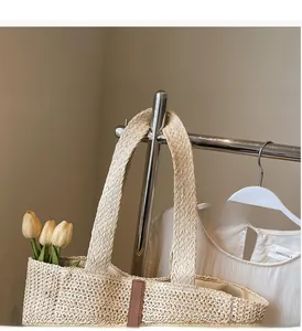 Détail d'un sac cabas en paille tissée avec garniture en cuir brun et large bandoulière