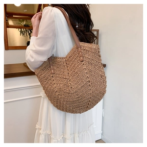 Detail of woven straw shoulder bag with leather handle and tight chevron pattern texture
