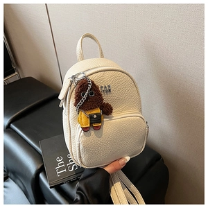 Détail du mini sac à dos beige texturé avec adorable pendentif chiot en peluche sur le devant