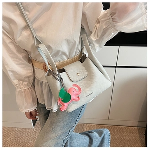 Detail of grey lychee leather bucket bag with cute elephant charm on a model