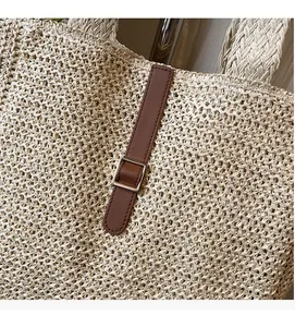Détail d'un sac en paille tressée avec texture beige et sangle en cuir marron à boucle