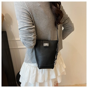 Detail view of black pebbled leather bucket bag with silver twist lock on model