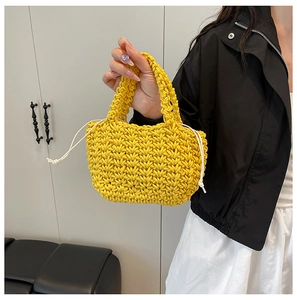 Detail of a bright yellow woven bucket bag with thick texture and white drawstring closure