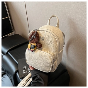 Détail d'un mini sac à dos en similicuir beige avec texture et pendentif ours mignon