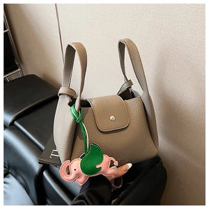 Detail view of taupe lychee leather bucket bag with top handles and elephant charm