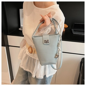 Detail of light blue bucket bag with lychee grain texture and metal twist lock