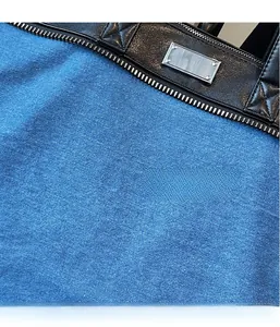 Macro shot of blue denim fabric with black leather trim and metal detail on the tote bag