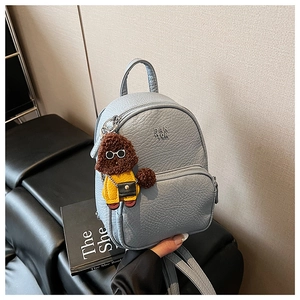 Vue détaillée du mini sac à dos en cuir bleu clair avec logo métal et pendentif chien