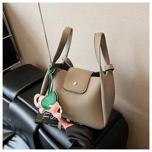 Detail of taupe pebbled leather tote bag featuring a cute elephant charm accessory